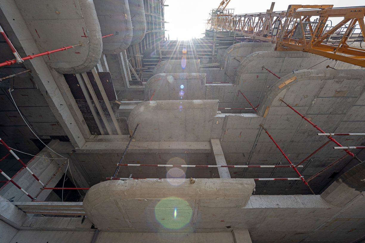 Pearl House By Imtiaz Construction site viewed from below, showcasing concrete structures, scaffolding, and sunlight filtering through.